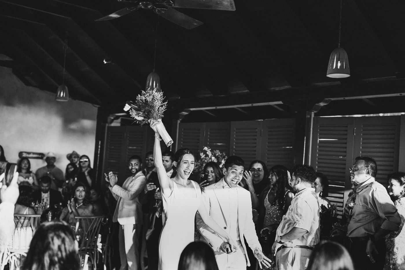 Black and white photo of energetic wedding reception dance floor celebration.