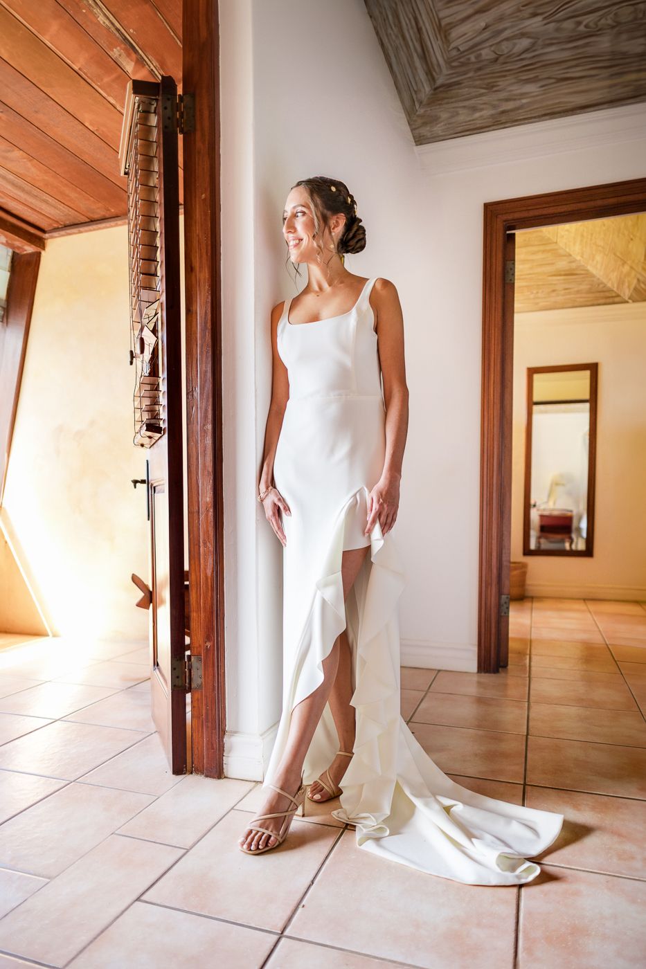 A series of elegant white wedding dress details showing the flowing fabric and train against light tile flooring.