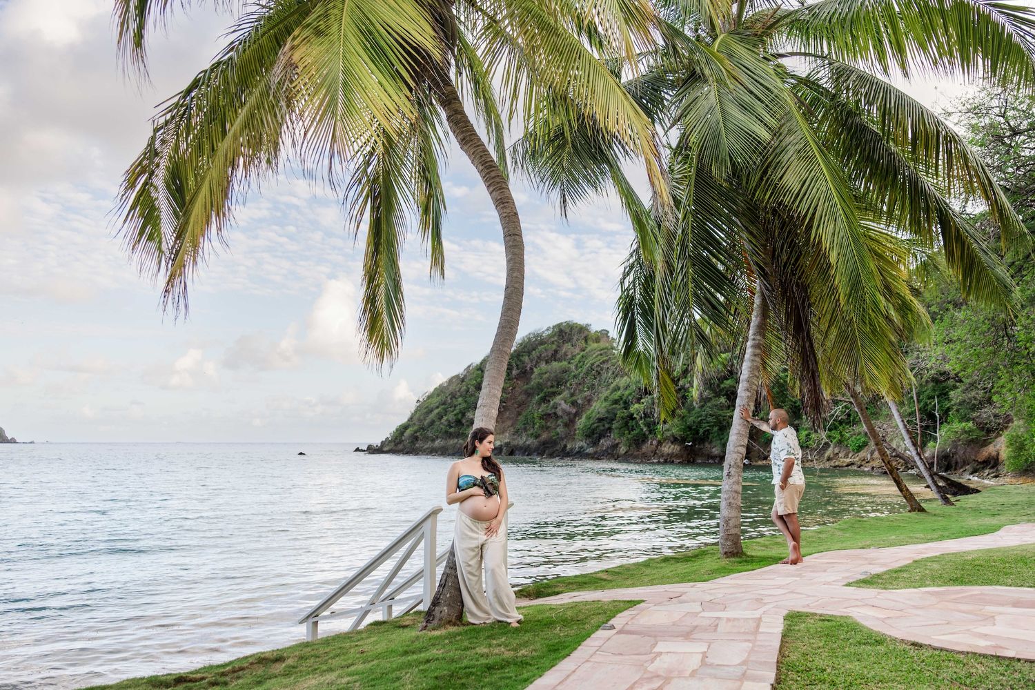 Couple embracing under tropical palm trees by the ocean at a scenic Caribbean beachfront resort.