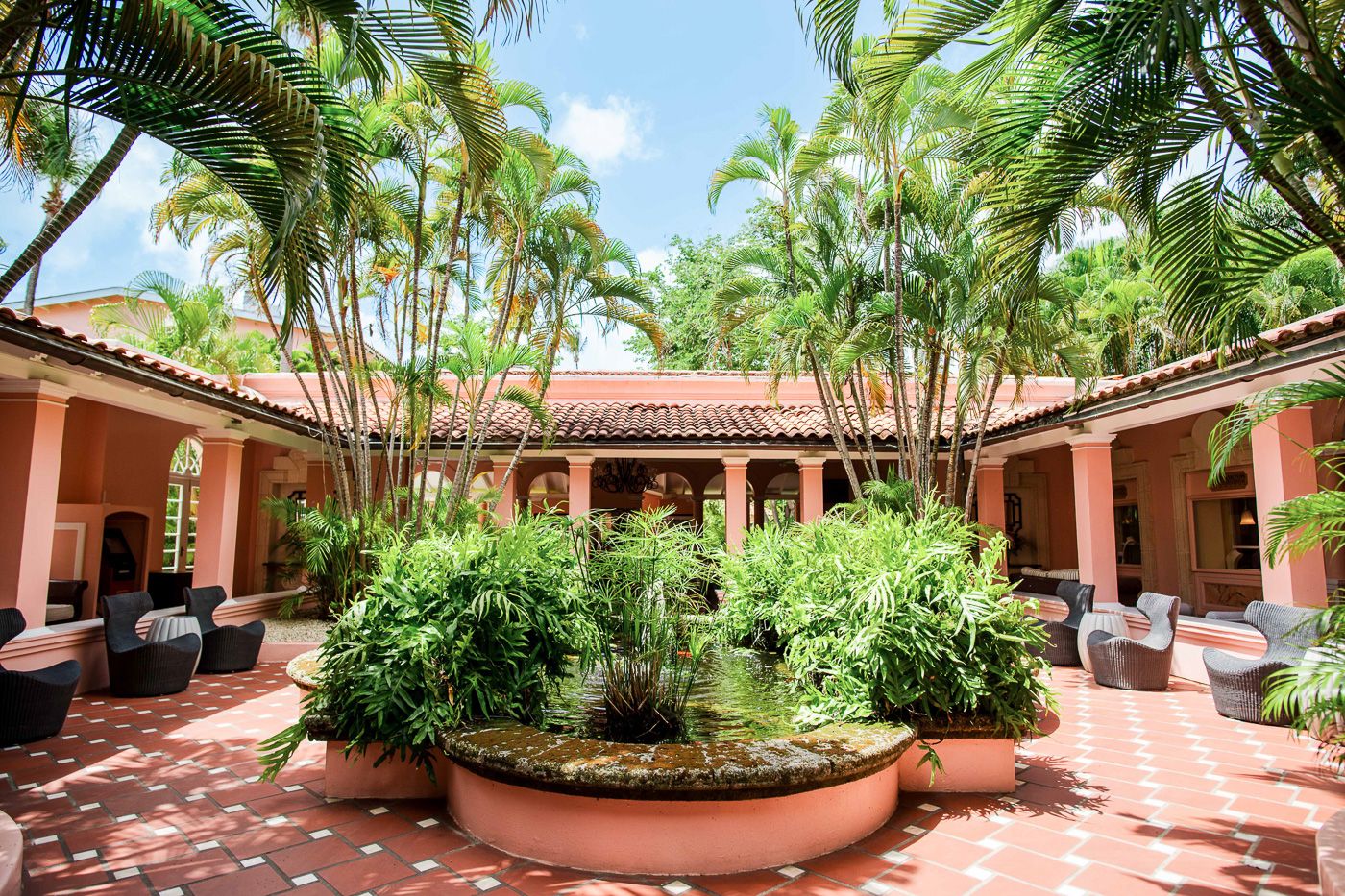 Mediterranean-style courtyard with palm trees and tropical landscaping surrounding a central garden feature.