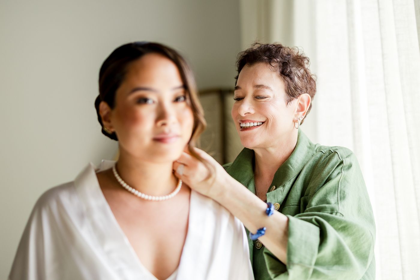 Intimate couple portrait session in a bright room wearing white and sage green clothing.