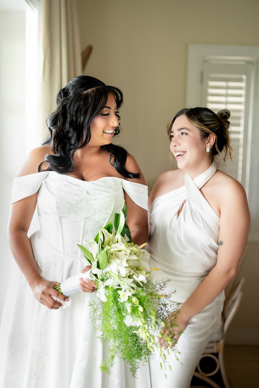Wedding party in white dresses with fresh green and white floral bouquets.