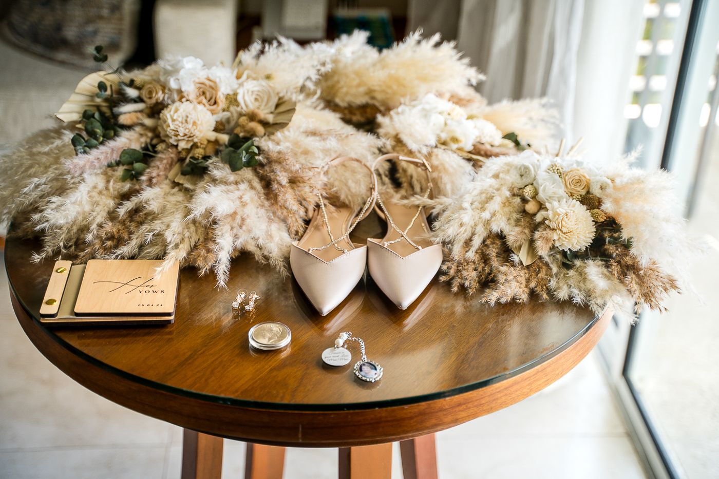 Wedding details displayed on wooden table with floral arrangements.