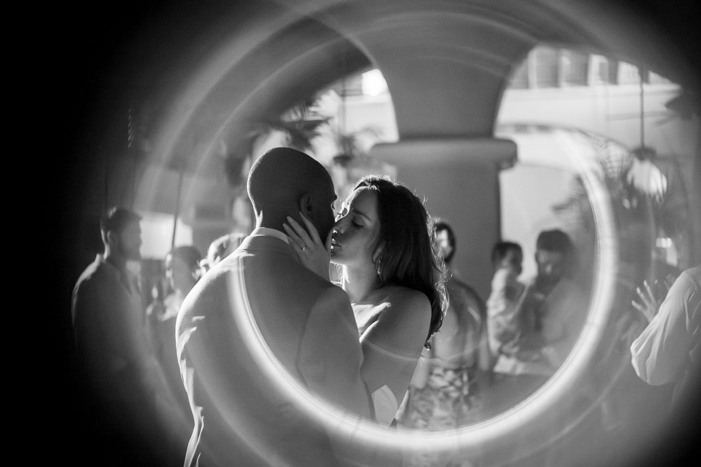 A dreamy circular framed photo of a couple dancing at their wedding reception.