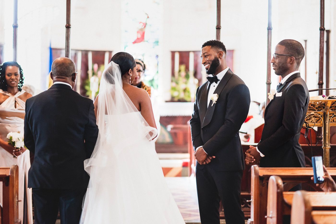 Intimate church wedding ceremony with guests seated in wooden pews and traditional decor.