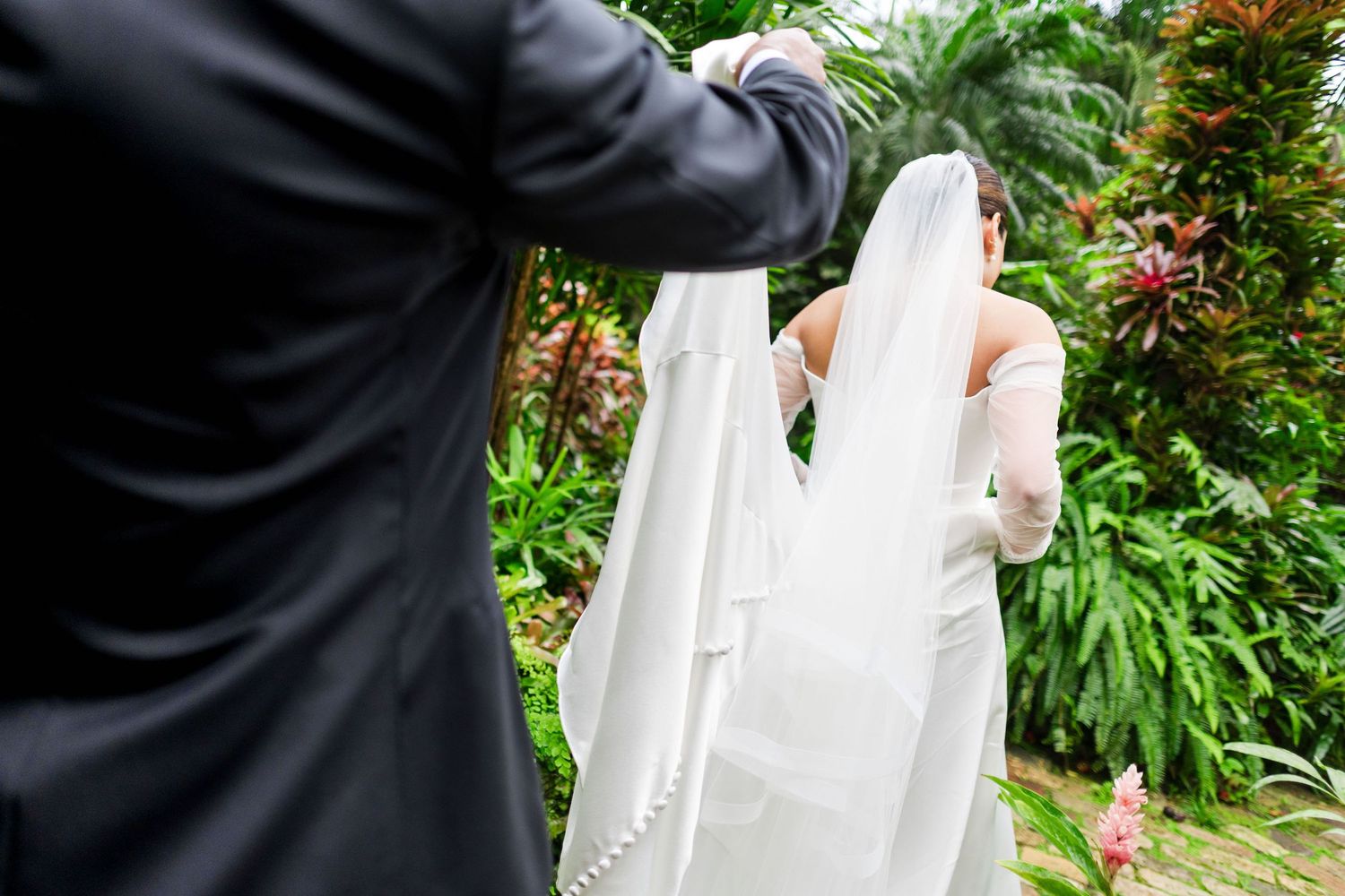 Wedding couple embracing in a lush garden setting with vibrant orange flowers.