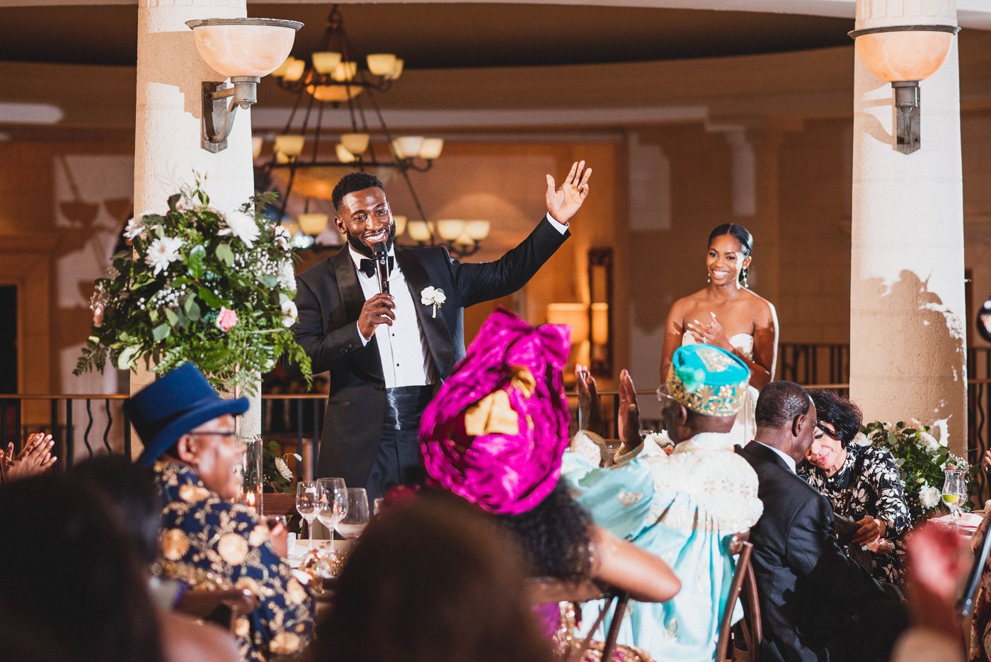 Wedding guests celebrating and dancing during evening reception with colorful lighting and decor.