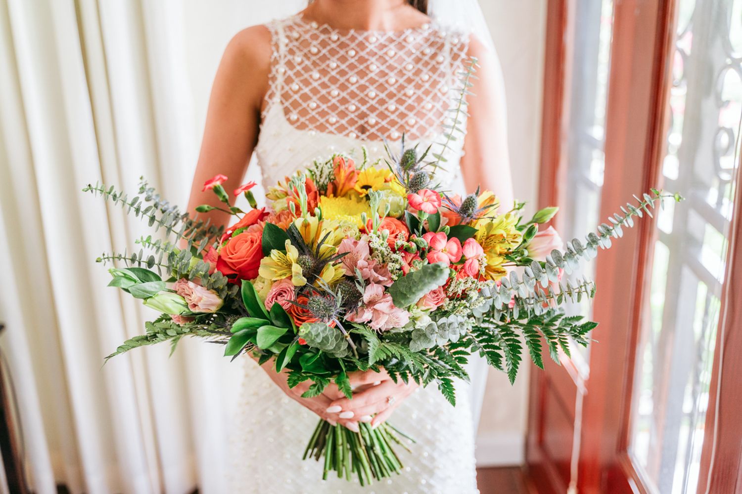 Three vibrant hand-tied bridal bouquets featuring mixed seasonal blooms in coral and peach tones with eucalyptus greenery.