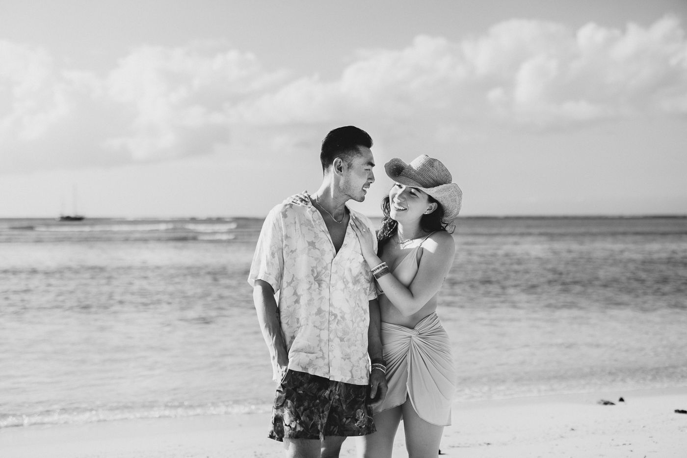Black and white beach engagement photo with waves crashing in background.