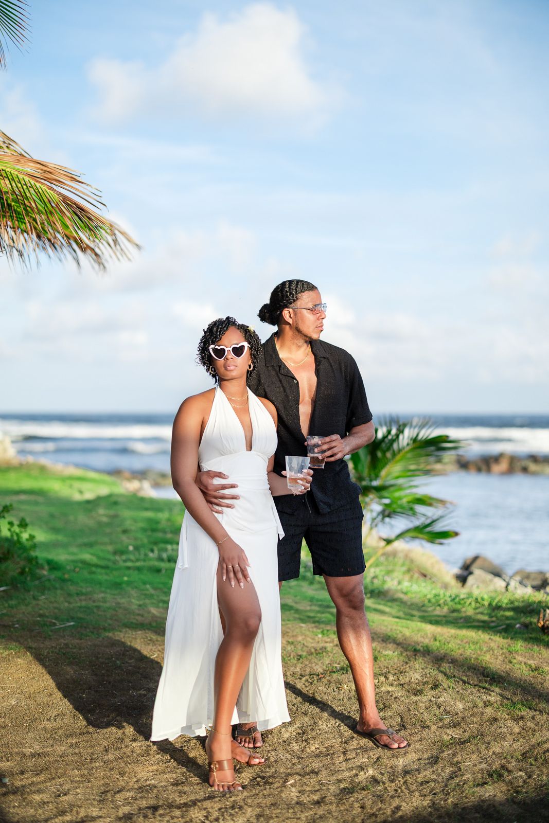 Two people enjoying a romantic moment on a scenic tropical beach with palm trees and ocean waves in the background.
