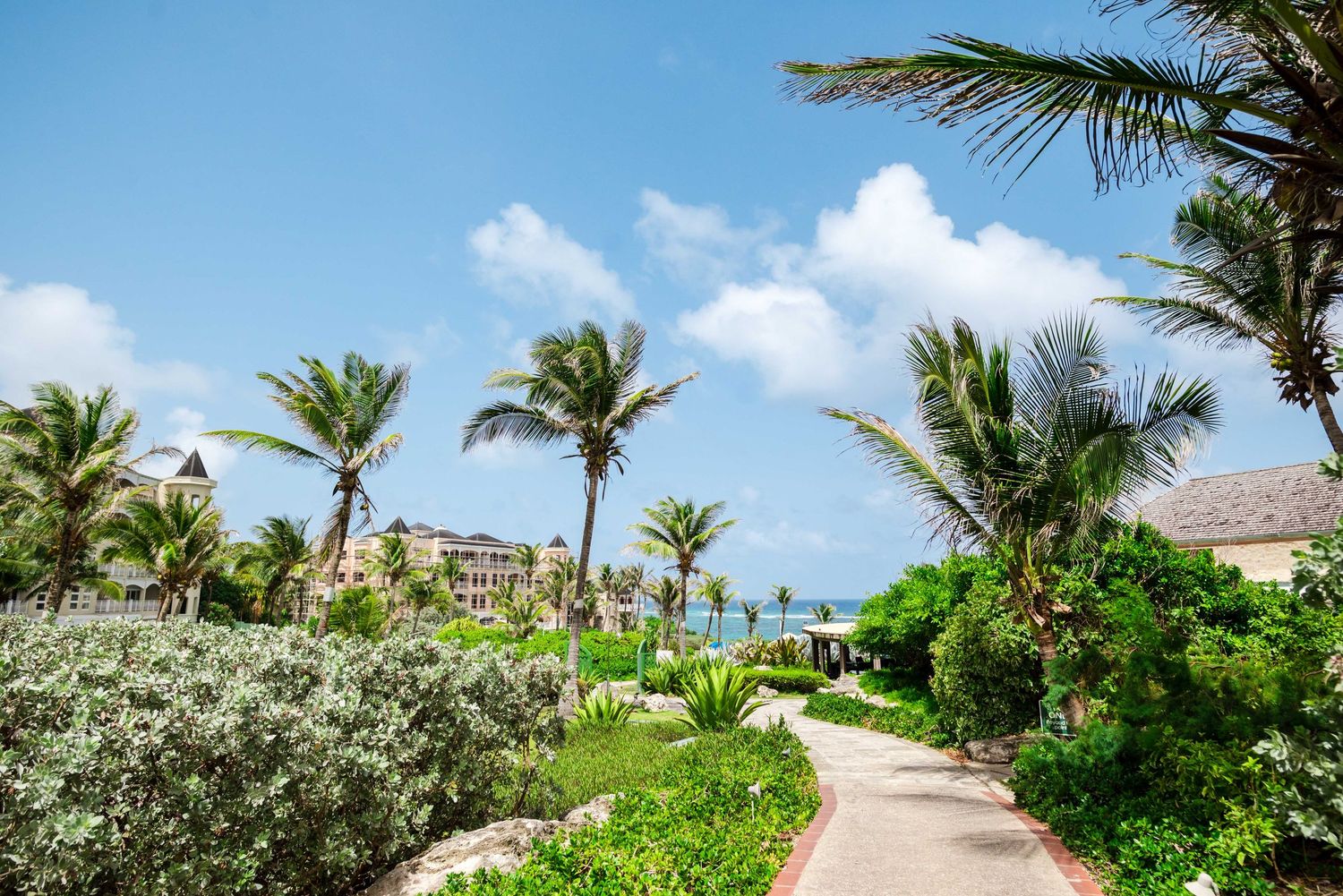 The crane resort barbados wedding venues, with palm trees leads to oceanfront condos under bright blue skies.