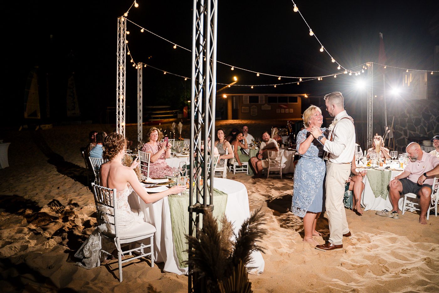 Wedding reception dance floor moments under string lights on the beach.