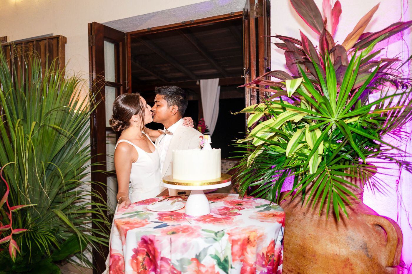 Wedding couple shares an intimate moment near their floral-decorated cake table.