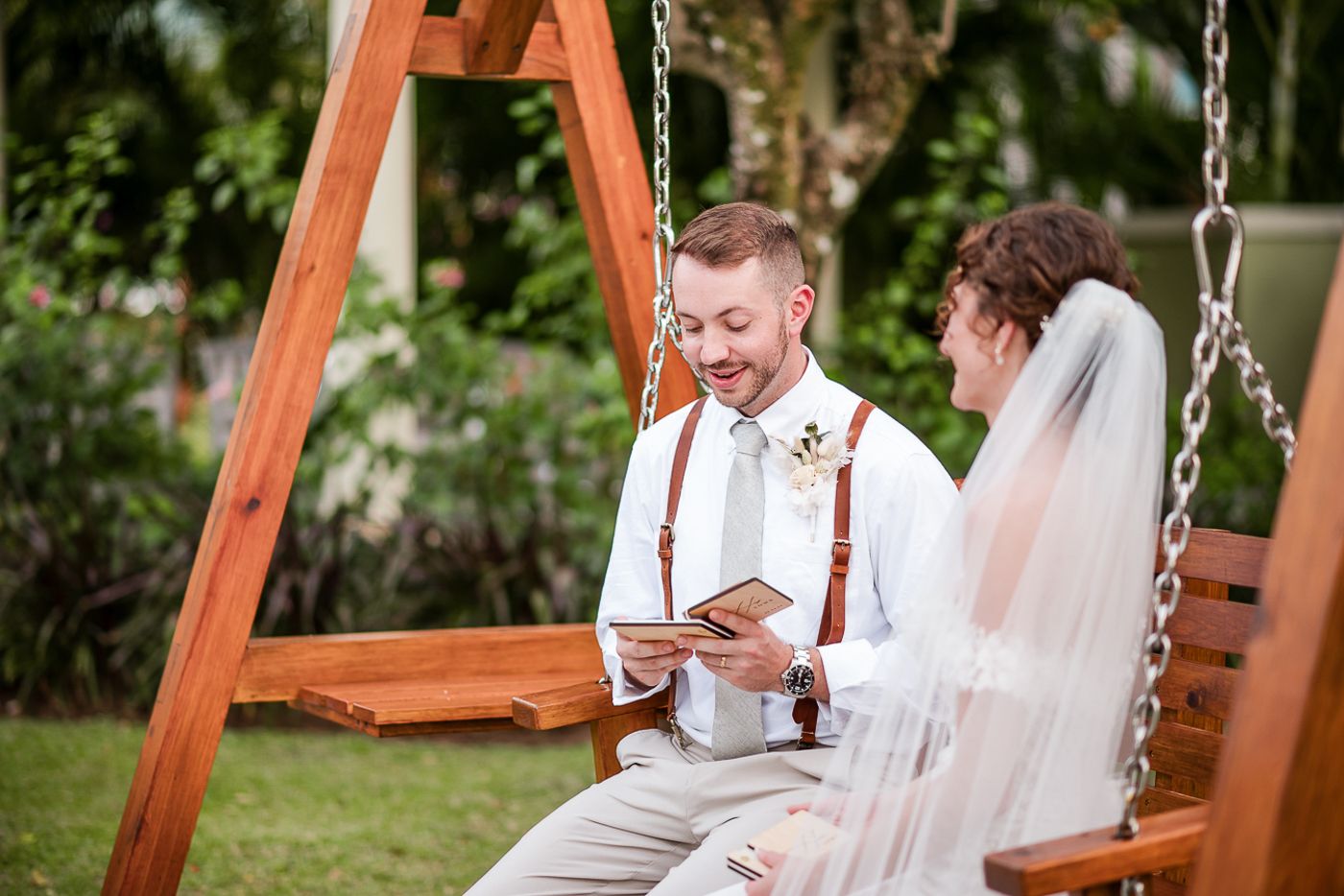 Romantic wedding portraits on wooden swing in tropical garden setting.
