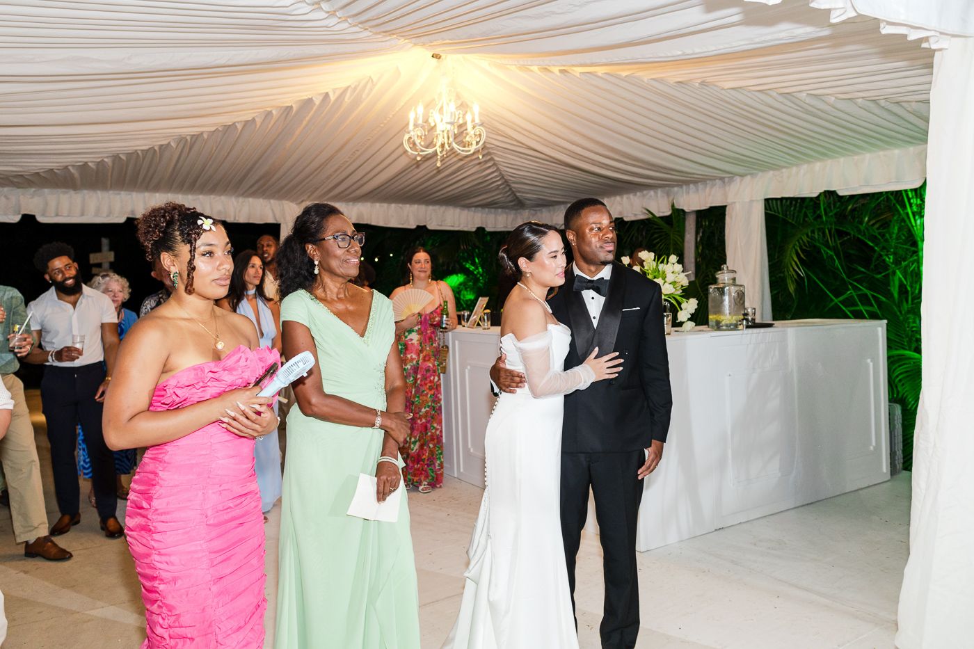 Elegant white draped ceiling with chandeliers decorates an indoor wedding reception space.