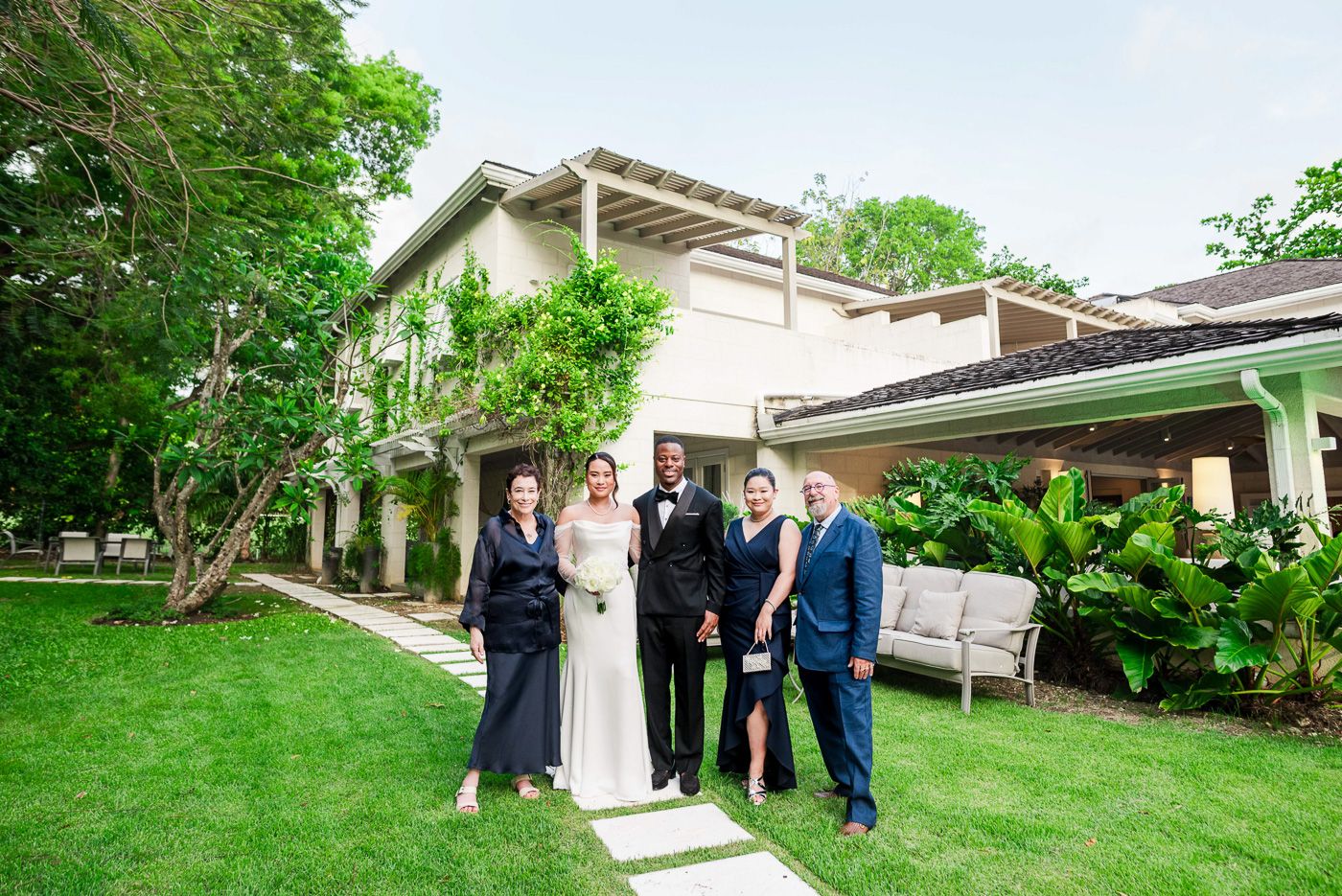 Lush green garden wedding venue with elegant white architectural details and stone pathways.