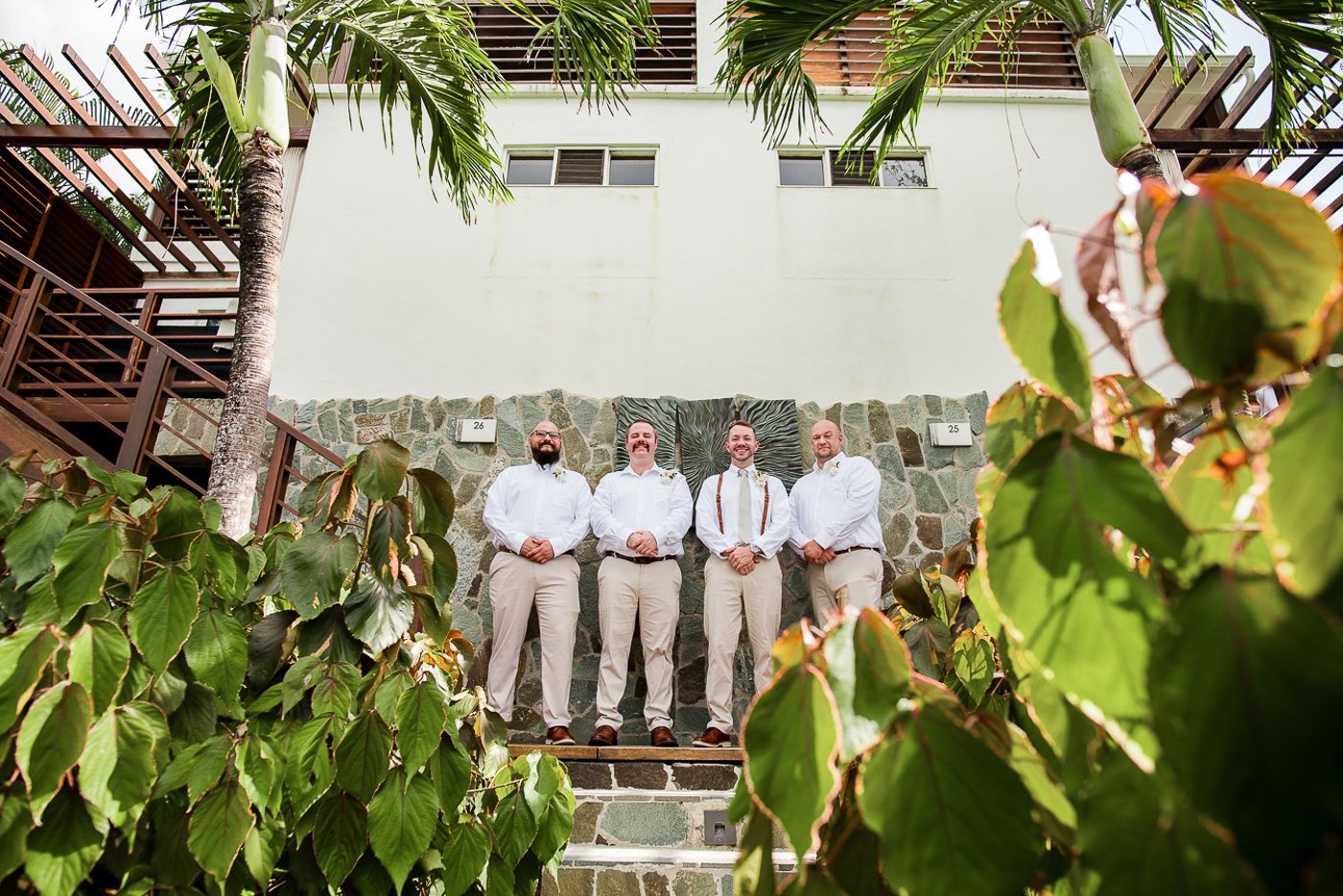 Outdoor group photo taken under tropical foliage and palm trees.