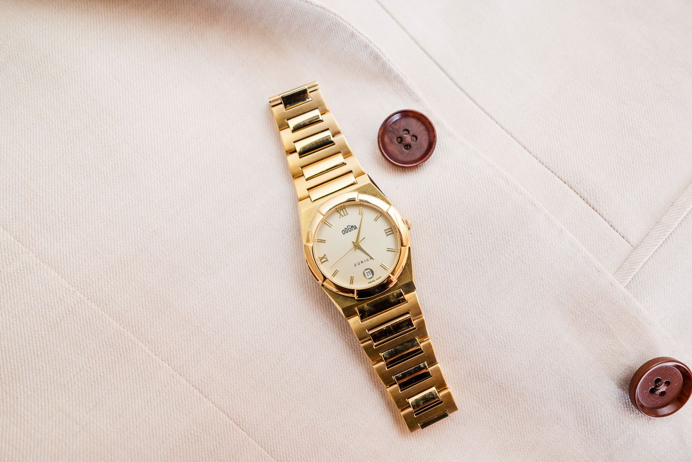 Gold watches and accessories arranged on white surface.