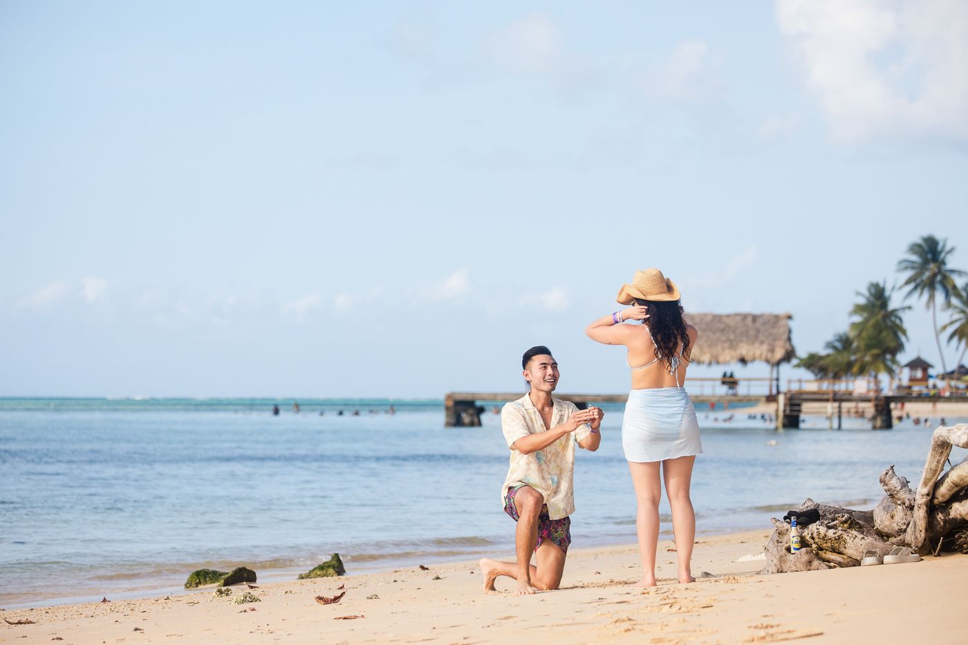 A proposal moment captured on a beautiful Caribbean beach with palm trees and turquoise water.