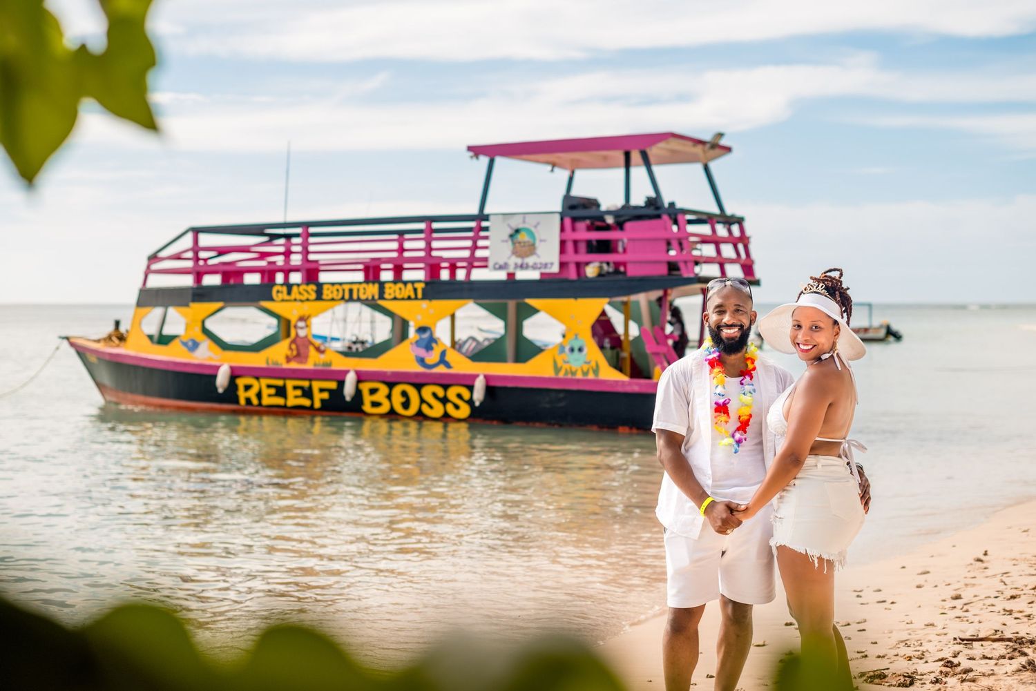 Bright pink and yellow tour boats docked at a tropical beach.