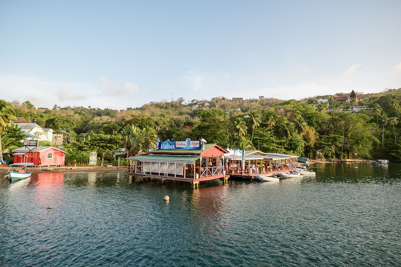 Scenic waterfront landscape with boats docked along a tropical coastline.