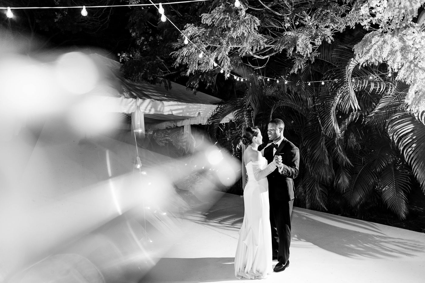 Black and white panoramic shot of couples dancing at an evening wedding reception.