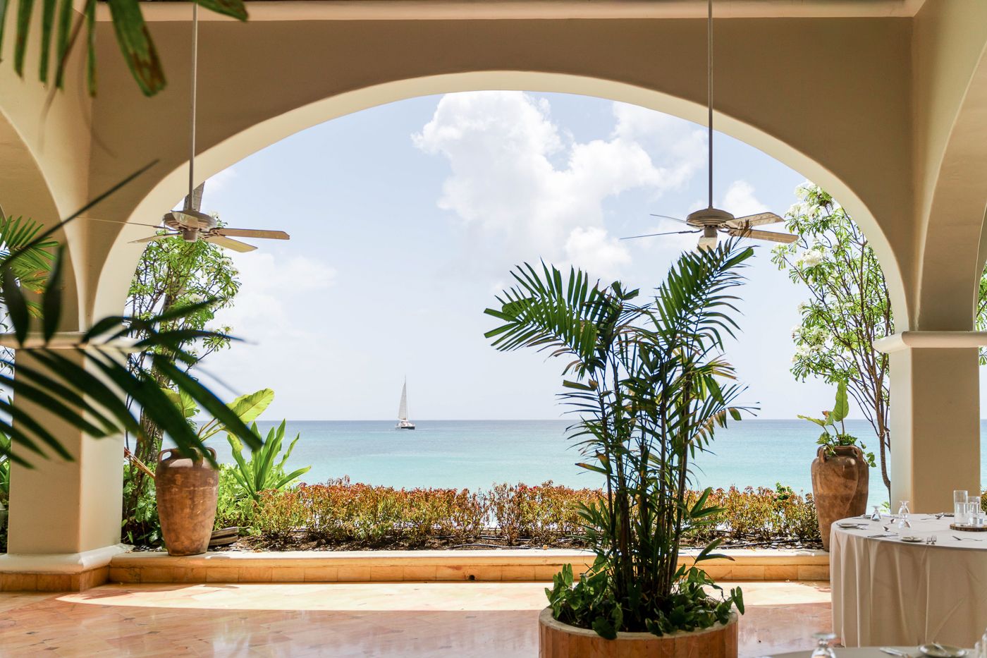 Beachfront terrace with arched columns and tropical plants overlooking the Caribbean Sea.