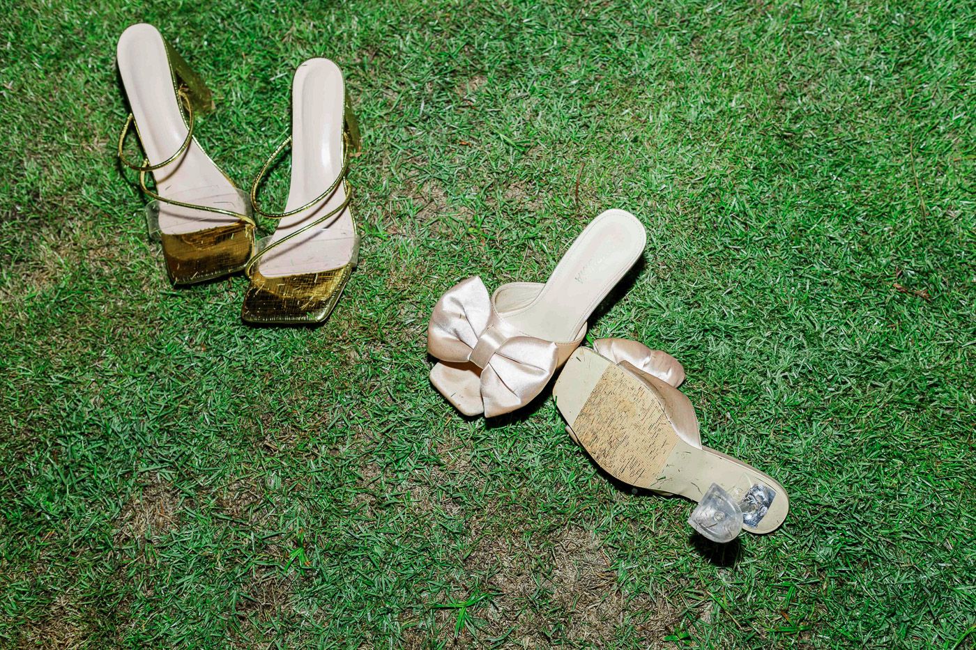 Wedding shoes arranged artistically on green grass.