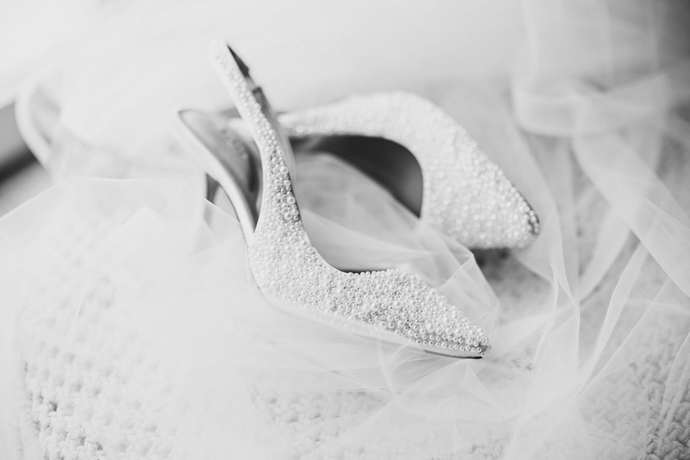 White lace bridal heel shoe photographed in soft focus with tulle veil. Sandy Lane barbados