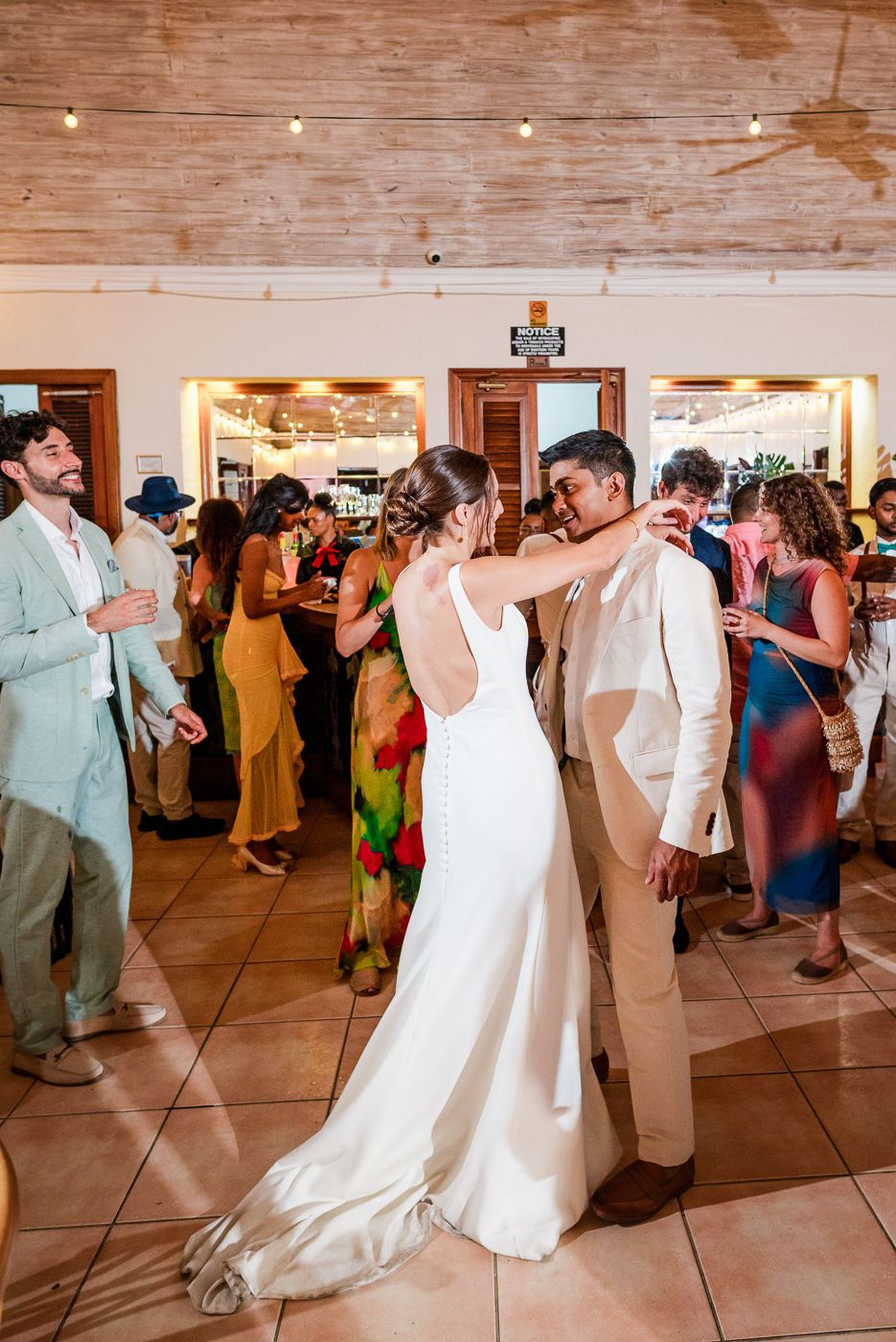 Wedding reception dance floor filled with celebrating guests under wooden beams.