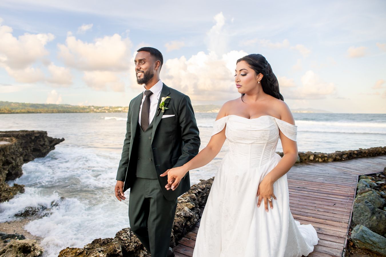 Wedding portraits on wooden boardwalk with dramatic ocean waves and sky.