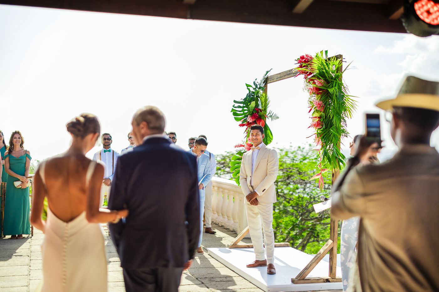 Outdoor wedding ceremony under floral arch with ocean vista backdrop.