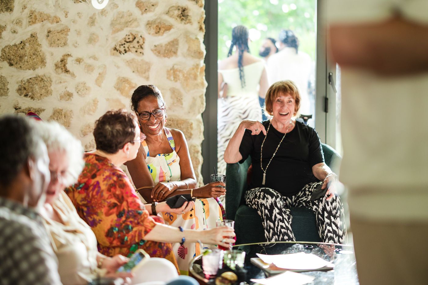 Guests socializing at tables inside a rustic stone wall venue with natural lighting.