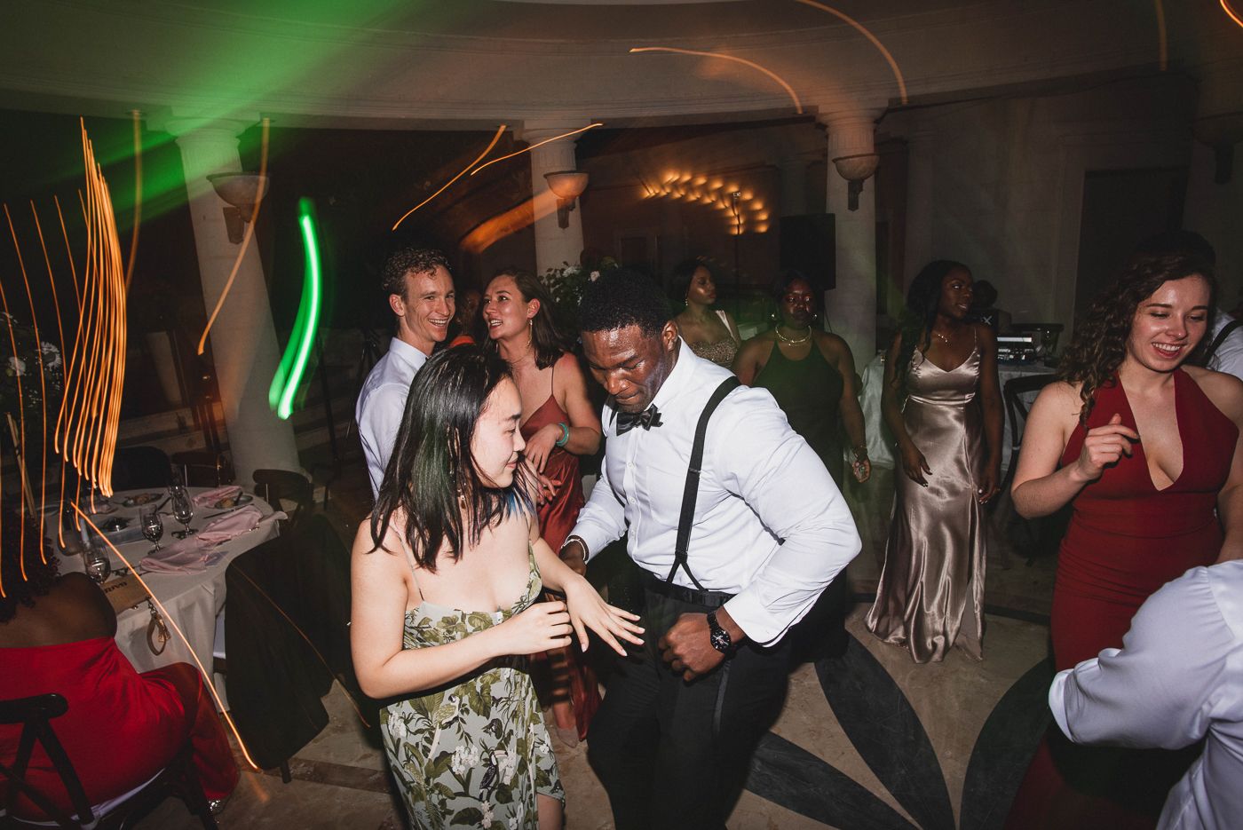 Wedding reception dance floor illuminated with green and orange lighting effects.