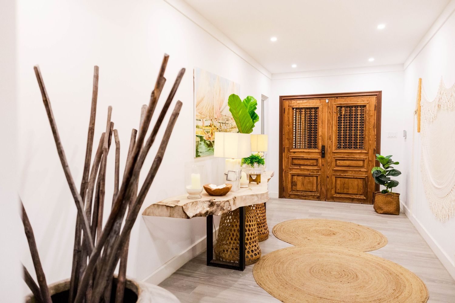 Bright and airy hallway design with white textured walls, wooden accents, and dried branches as decor elements. luxury villa in barbados