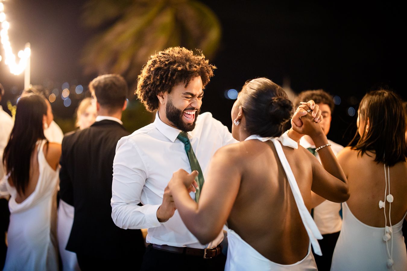 Wedding guests dancing and celebrating on an outdoor dance floor at night.