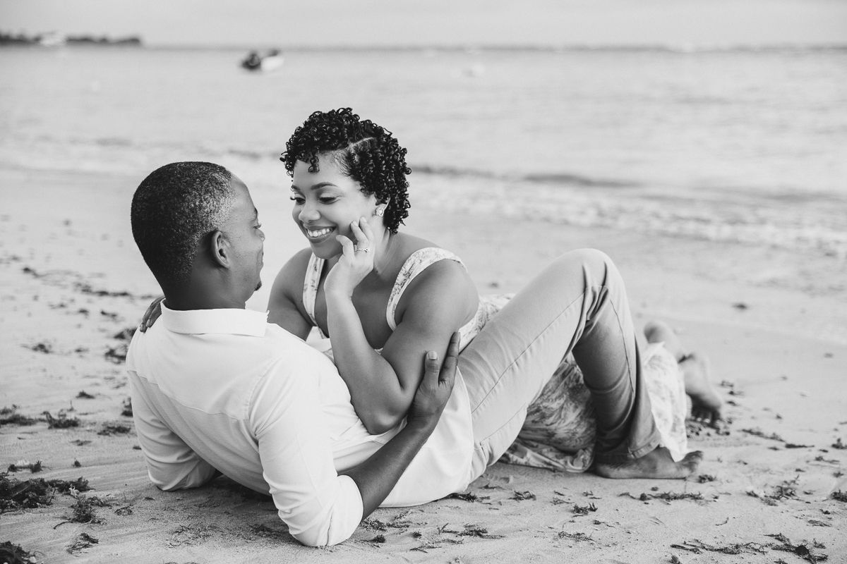 A romantic black and white photo series of a couple sharing tender moments together on a sandy beach.