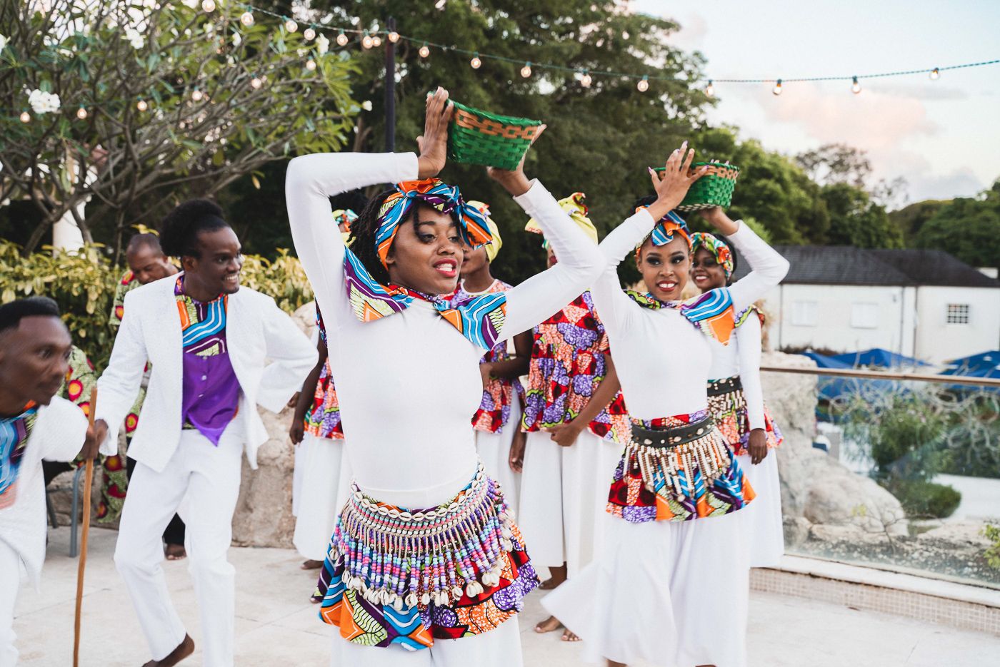 Wedding guests wearing traditional Mexican folk dresses and colorful attire dancing at an outdoor celebration.
