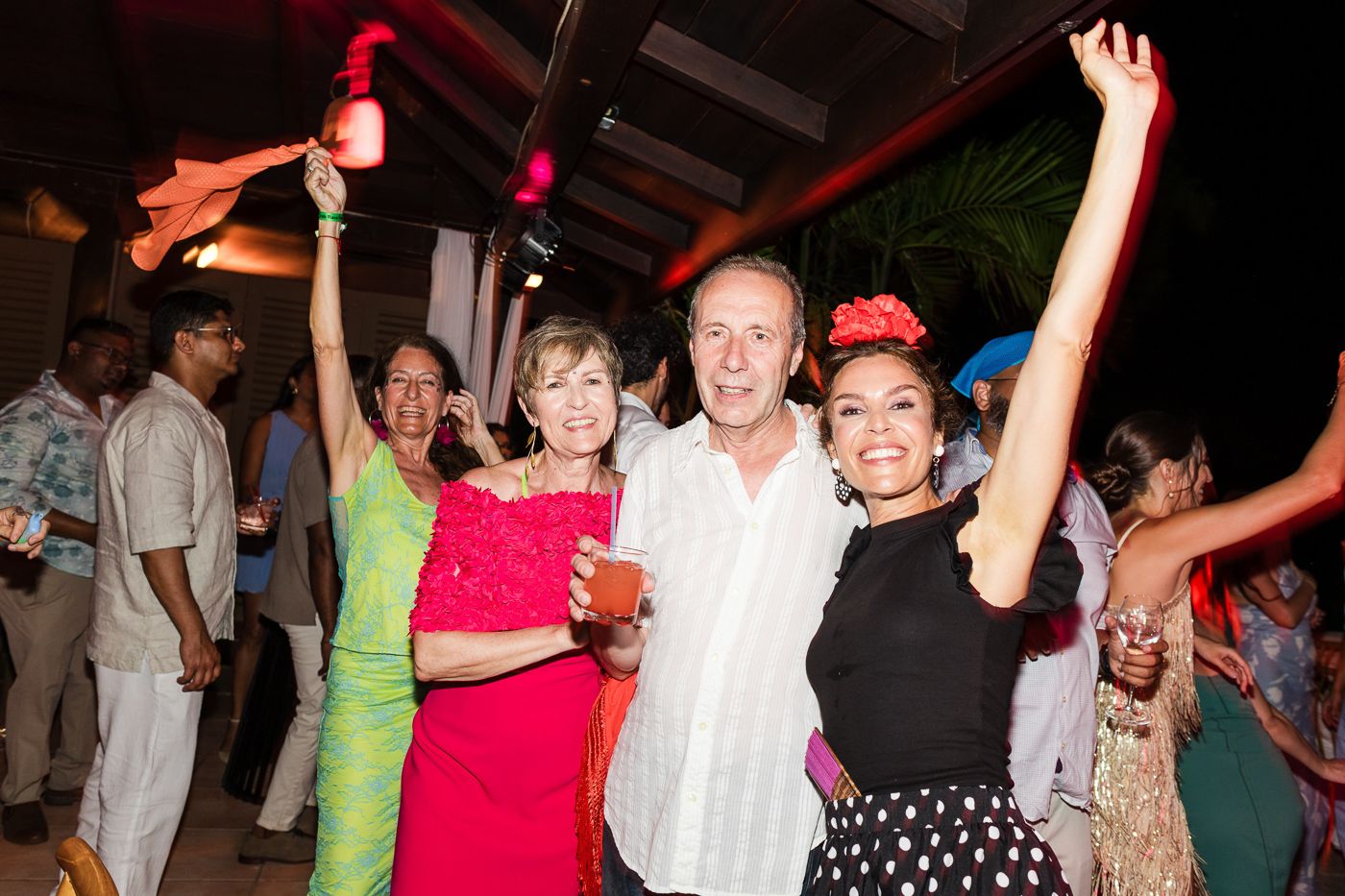 Party guests celebrate with raised arms during a festive nighttime reception.