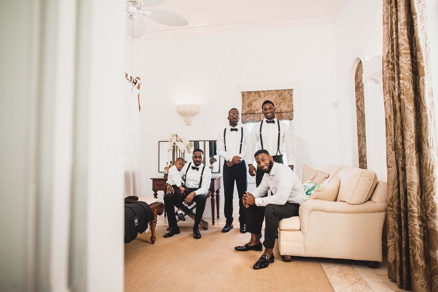 Wedding party members in formal attire gather in elegant room before ceremony.