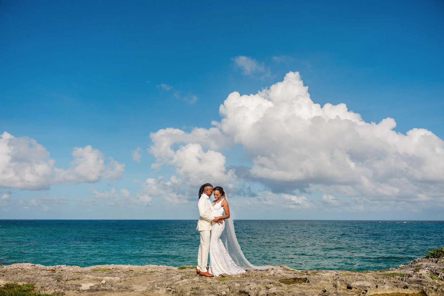 Destination beach wedding photography with dramatic blue sky and ocean backdrop.