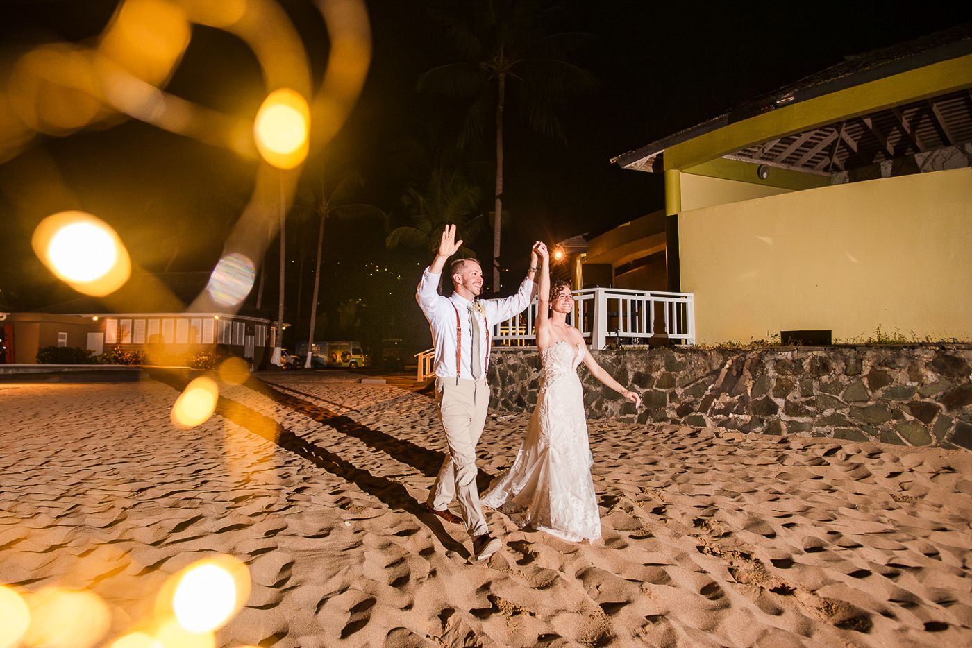 String lights illuminate an intimate beach wedding reception setup at dusk.