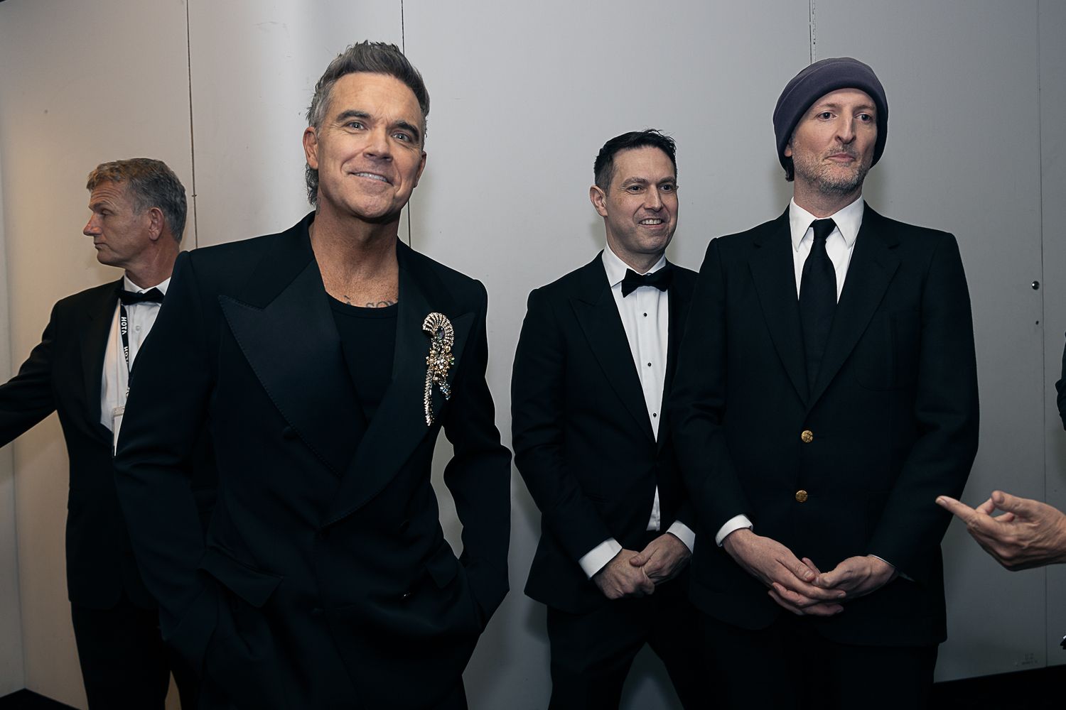 Formal group portrait of people in black and white attire against a gray background.