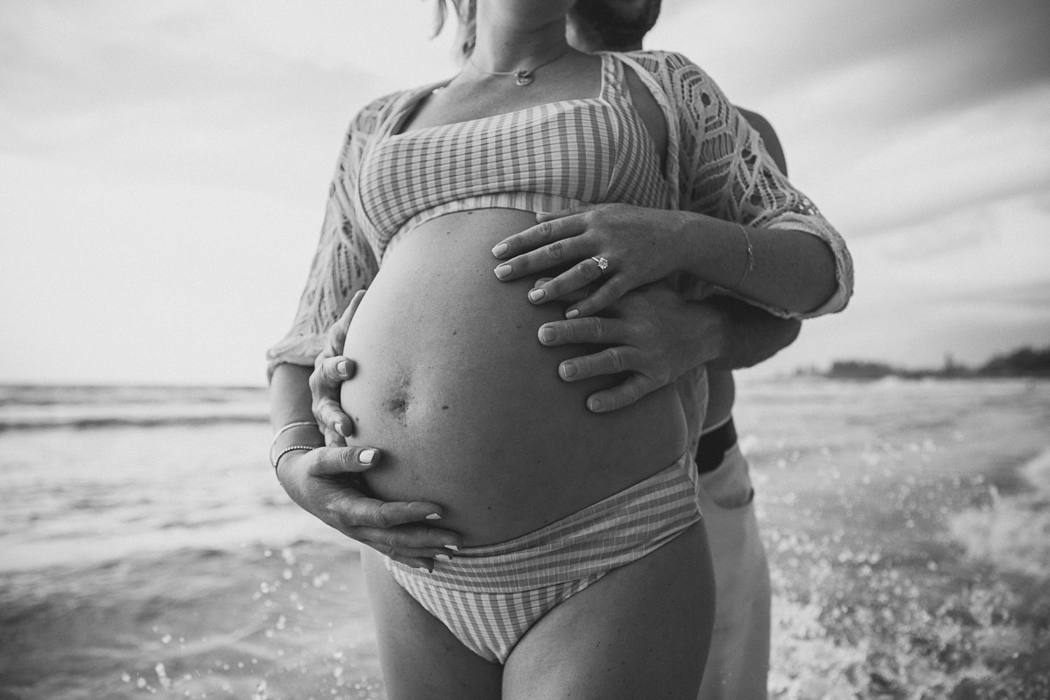 Intimate maternity photos captured on a cloudy beach.