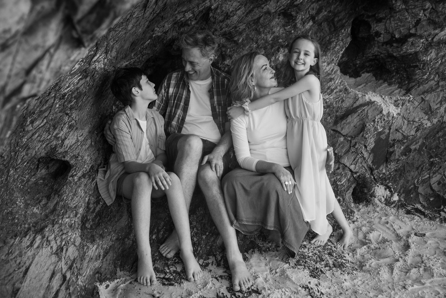 Children sitting together on a rocky surface outdoors during a casual gathering.