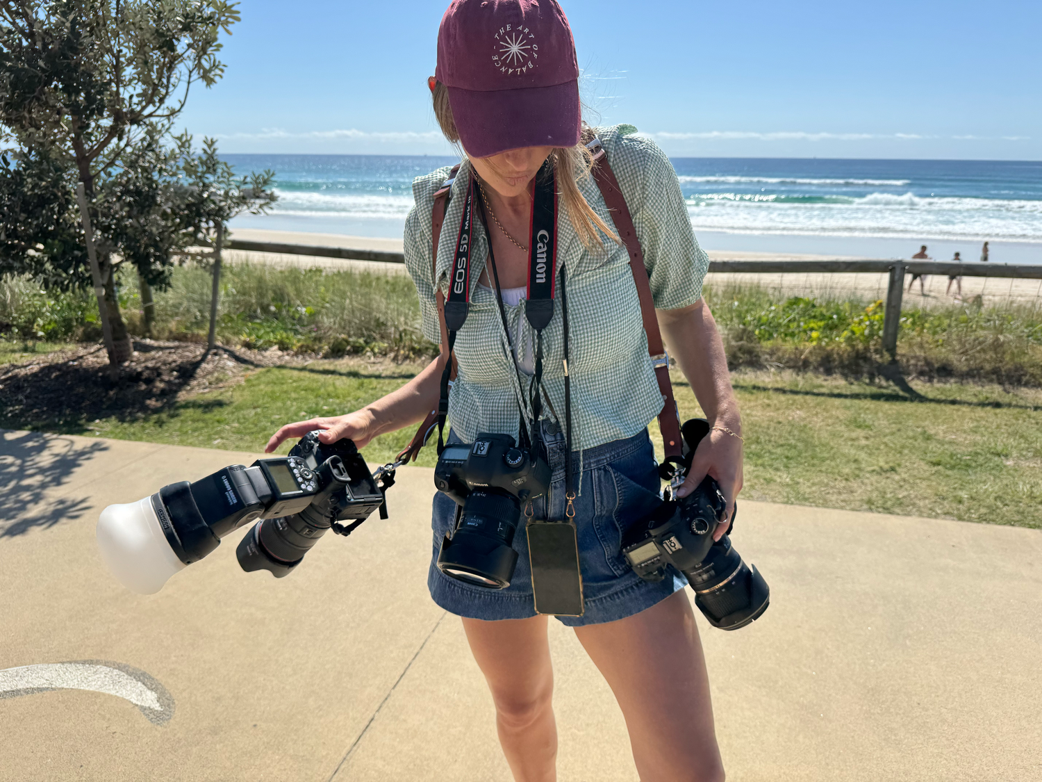 Professional cameras and photography equipment set up along a sunny beachfront location.