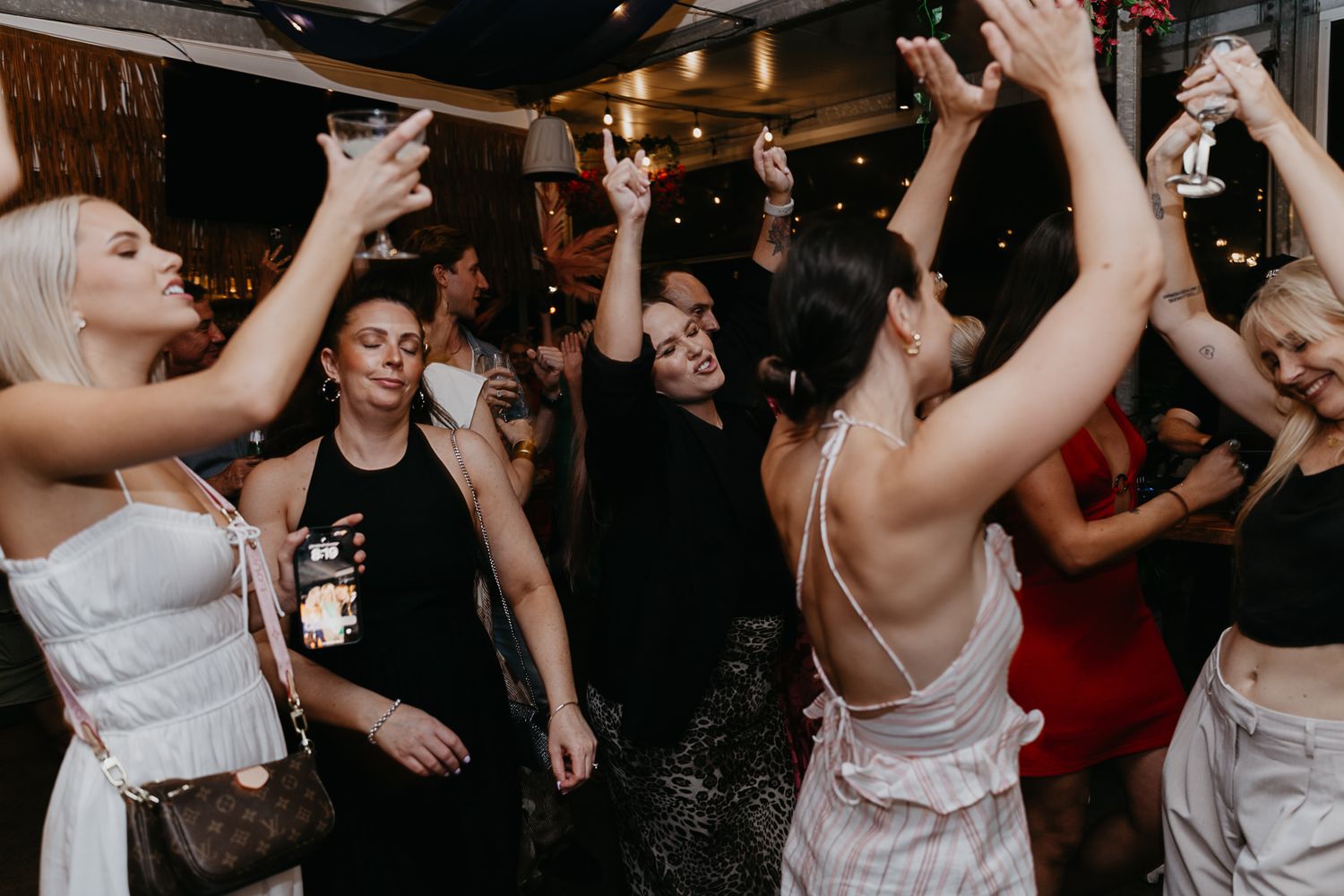 Wedding guests dancing and celebrating on a dark dance floor.