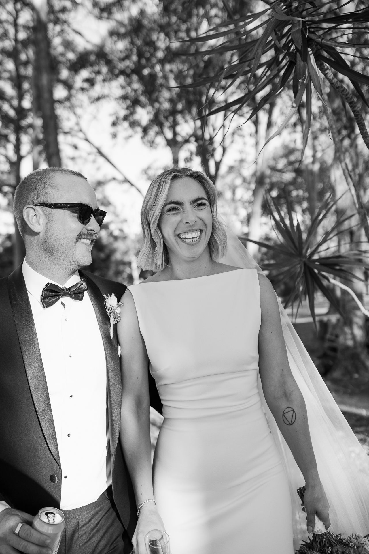Wedding couple shares joyful laughter together outdoors in natural lighting.