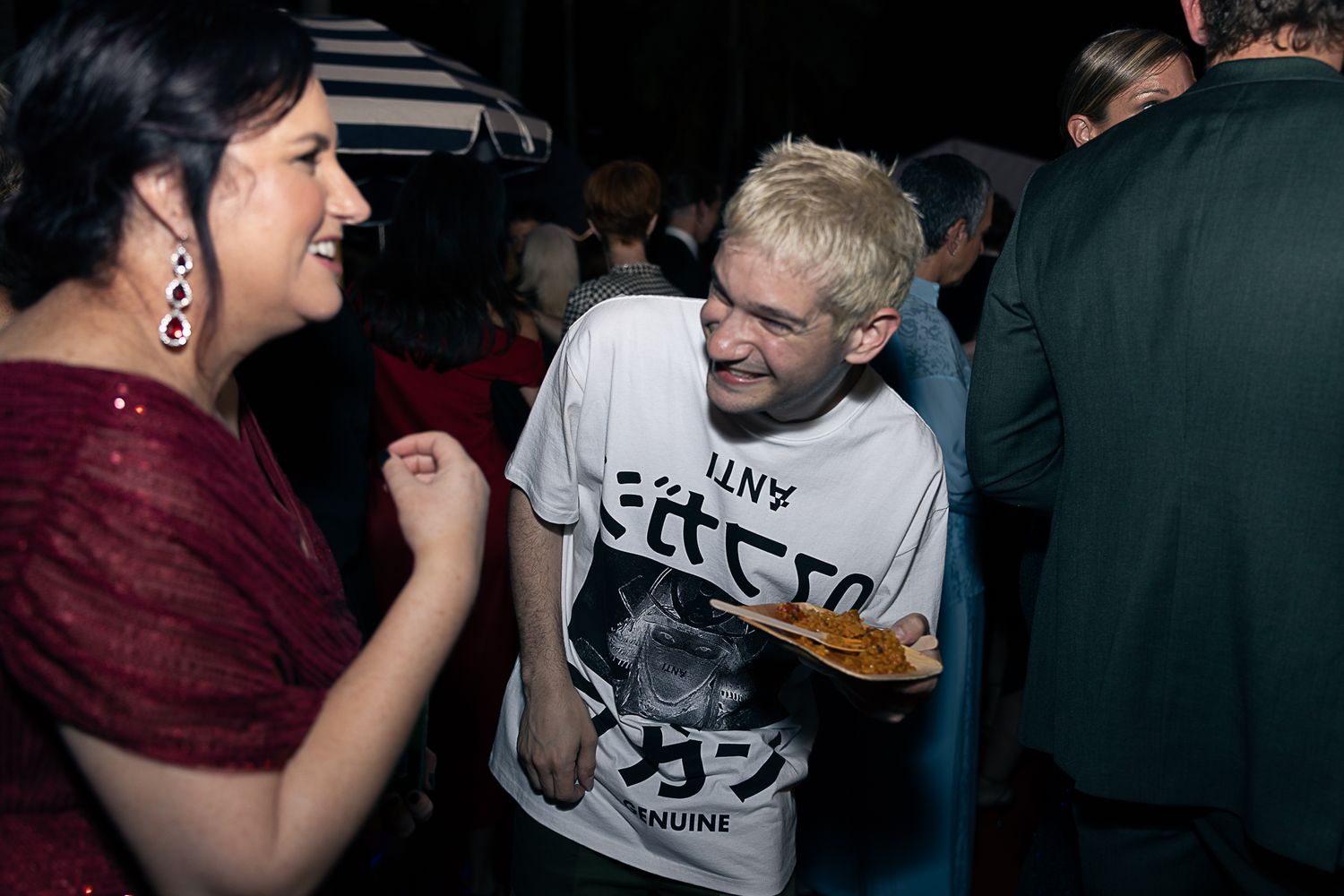 People mingling and socializing at a dimly lit evening party.