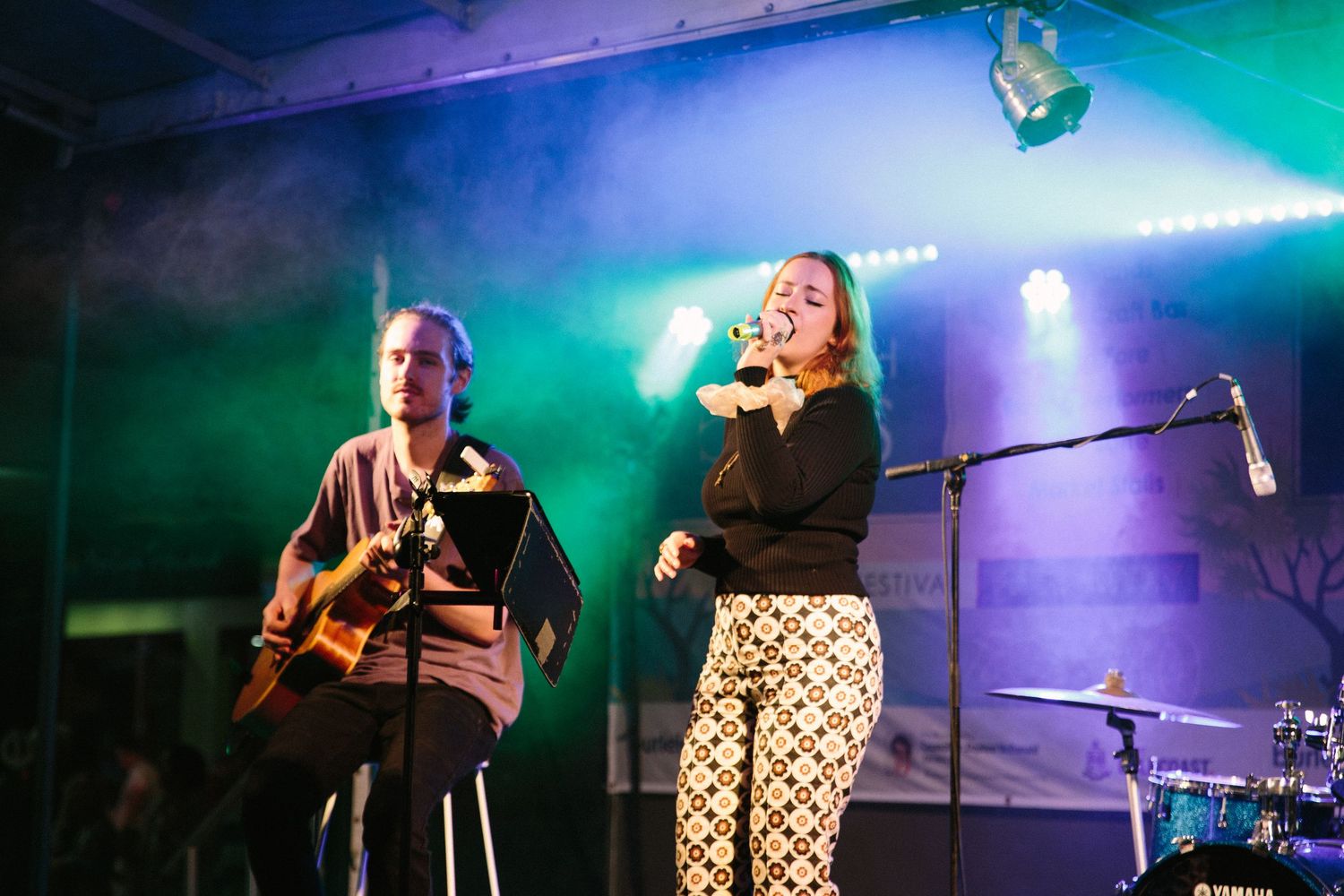 Live music performance on stage with blue and green theatrical lighting.